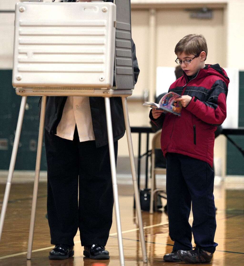 U.S. Citizens Head To The Polls To Vote In Presidential Election - STERLING HEIGHTS, MI, - NOVEMBER 6: A young boy reads a book while his parent votes in the U.S. presidential election at Carleton Middle School November 6, 2012 in Sterling Heights, Michigan. Recent polls show that U.S. President Barack Obama and Republican presidential candidate Mitt Romney are in a tight race. (Photo by Bill Pugliano/Getty Images)