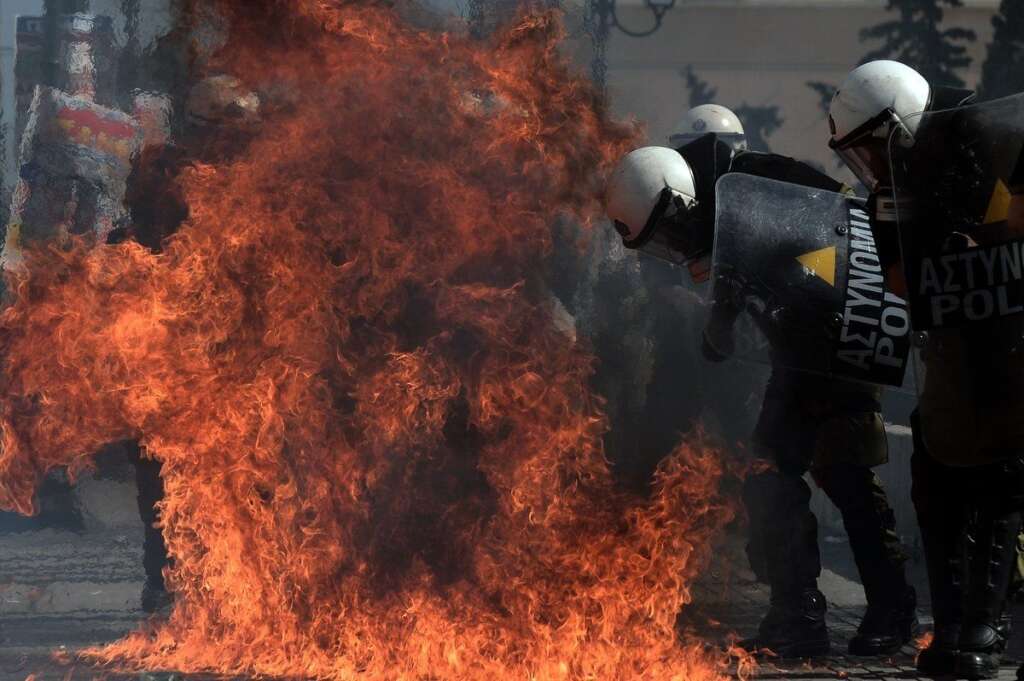 GREECE-FINANCE-PUBLIC-DEBT-EU-DEMO - A fireboomb explodes near riot police during clashes with demonstrators during a 24-hour strike in Athens on October 18, 2012. Greek riot police fired tear gas to disperse protesters at an anti-austerity rally in Athens held during a national general strike as EU leaders were to tackle the eurozone crisis at a summit. The protesters had broken through a police line outside luxury hotels on central Syntagma Square and scattered groups of youths later attacked police with stones and firebombs, an AFP reporter said.  AFP PHOTO / ARIS MESSINIS        (Photo credit should read ARIS MESSINIS/AFP/Getty Images)
