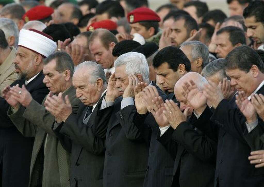 Les funérailles de Yasser Arafat - Sitôt après la mise en terre (de la terre de Jérusalem convoyée par camion pour l’occasion), la foule entame une prière, accompagnée par les dirigeants palestiniens, dont le numéro un de l’Organisation de libération de la Palestine (OLP) Mahmoud Abbas (au centre).