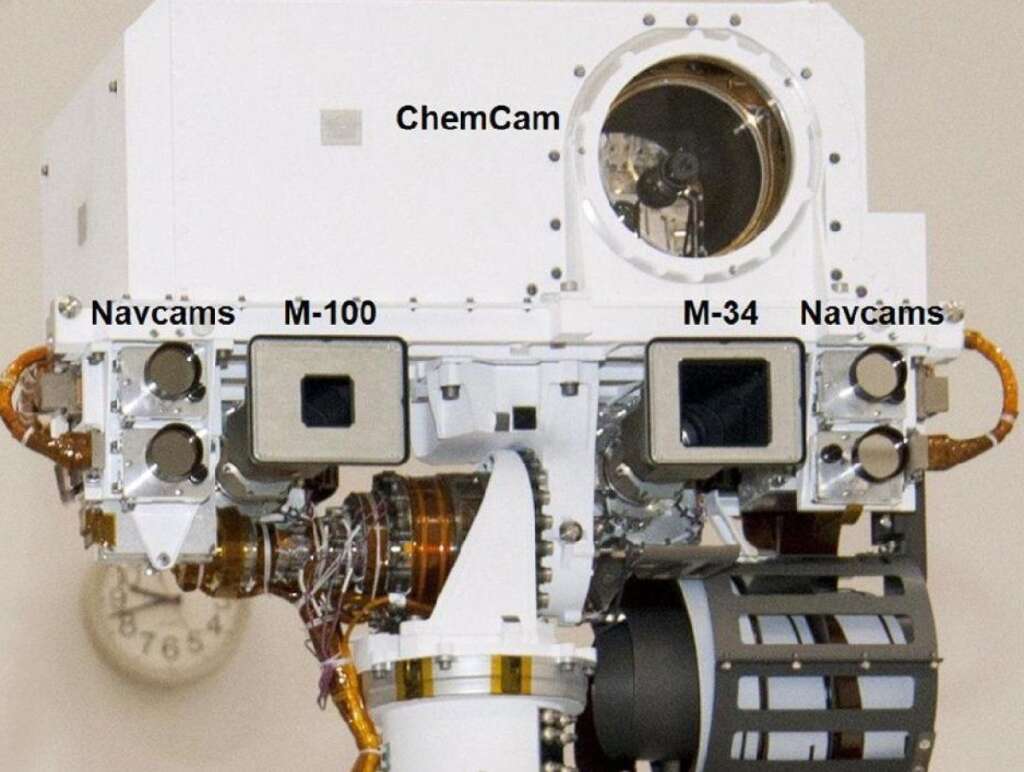 Head of Mast on Mars Rover Curiosity - This view of the head of the remote sensing mast on the Mars Science Laboratory mission's rover, Curiosity, shows seven of the 17 cameras on the rover. Two pairs of Navigation cameras (Navcams), among the rover's 12 engineering cameras, are the small circular apertures on either side of the head. On the top are the optics of the Chemistry and Camera (ChemCam) investigation, which includes a laser and a telescopic camera.     The Mast Camera (MastCam) instrument includes a 100-millimeter-focal-length camera called MastCam-100 or M-100, and a 34-millimeter-focal-length camera called the MastCam-34 or M-34. The two cameras of the MastCam are both scientific and natural color imaging systems. The M-100 looks through a 1.2-inch (3-centimeter) baffle aperture, and the M-34 looks through a 2.1-inch (5.3-centimete) baffle aperture. (NASA)