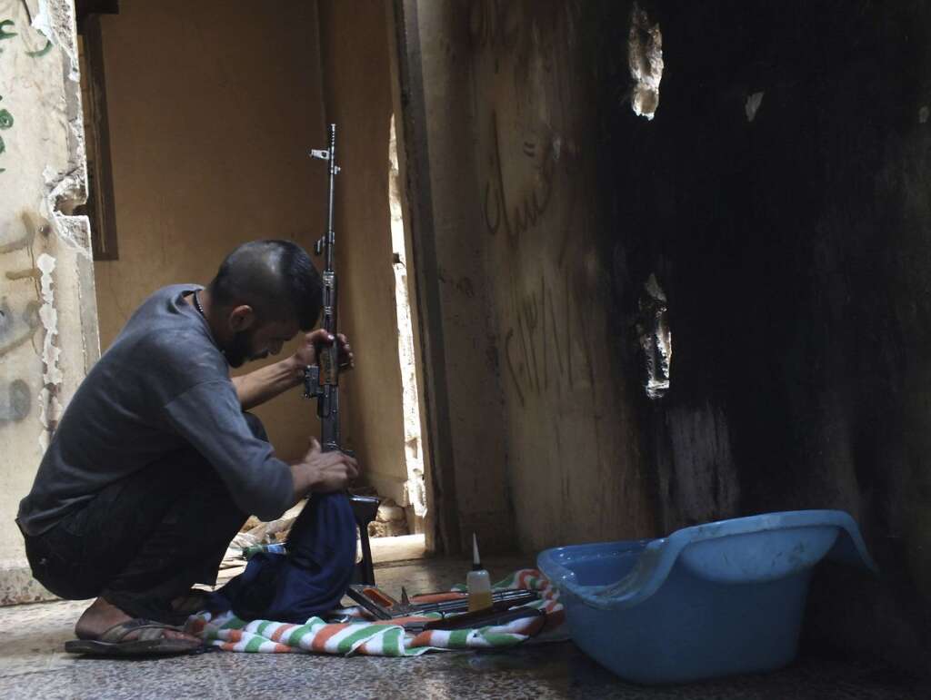 - Homs, le 22 août 2013. Un rebelle nettoye son arme, à l'abri.