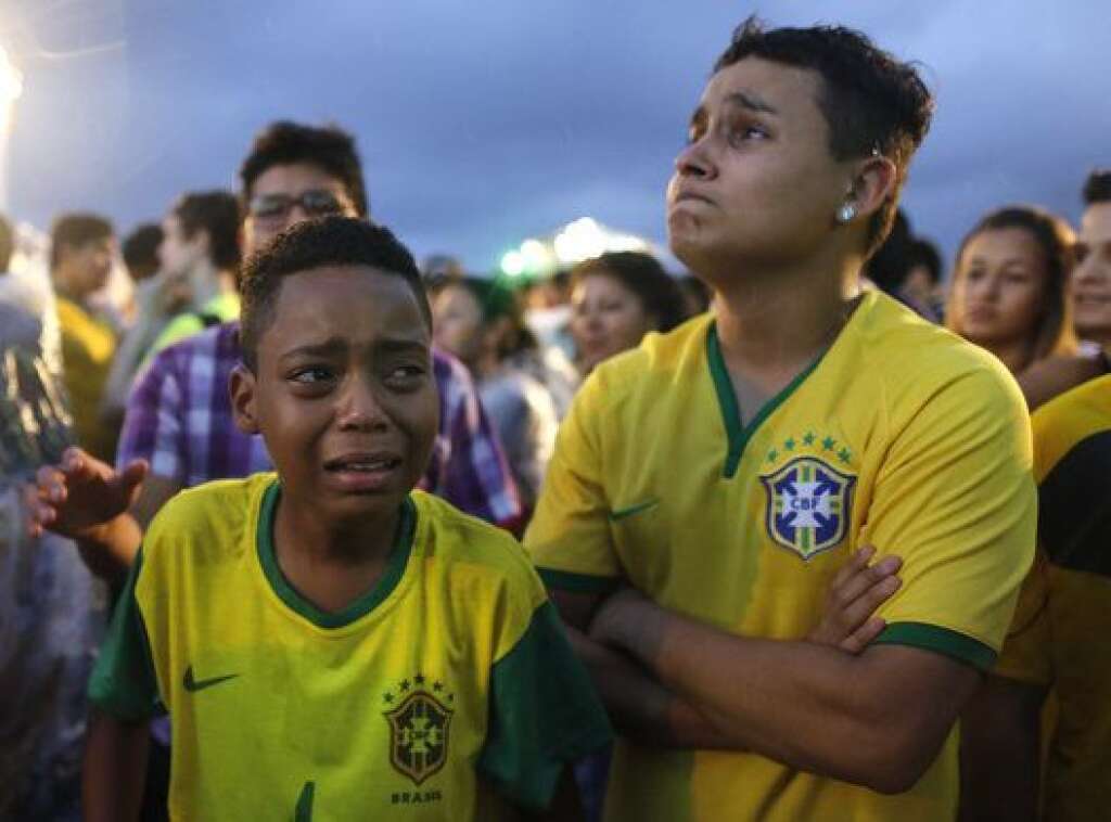 Brazil Soccer WCup - Brazil soccer fans cry as they watch their team get beat during a live telecast of the semi-finals World Cup soccer match between Brazil and Germany, inside the FIFA Fan Fest area on Copacabana beach in Rio de Janeiro, Brazil, Tuesday, July 08, 2014. (AP Photo/Leo Correa)