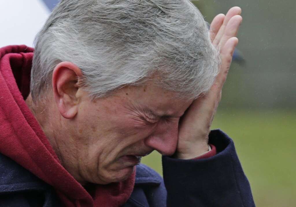 Sandy Hook Elementary School Shooting - A man reacts at the site of a makeshift memorial for school shooting victims in Newtown, Conn., Sunday, Dec. 16, 2012. A gunman opened fire at Sandy Hook Elementary School in the town, killing 26 people, including 20 children before killing himself on Friday. (AP Photo/Charles Krupa)