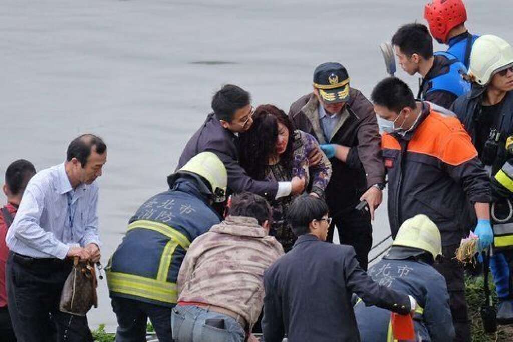 An injured passenger (C) is helped onto land by emergency personnel along the river bank after a TransAsia ATR 72-600 turboprop plane crash-landed into the Keelung river outside Taiwan's capital Taipei in New Taipei City on February 4, 2015. The low-flying passenger plane, TransAsia Flight GE235 with 58 people on board, clipped a road bridge and plunged into the river outside Taiwan's capital with at least nine feared dead and many trapped inside.   AFP PHOTO / SAM YEH        (Photo credit should read SAM YEH/AFP/Getty Images)