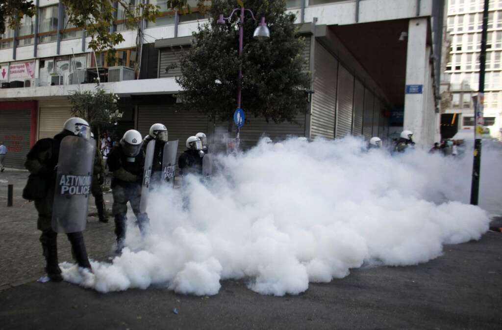 - Riot police are seen through tear gas during clashes during the 24-hour nationwide general strike in Athens on Thursday, Oct. 18, 2012. Hundreds of youths pelted riot police with petrol bombs, bottles and chunks of marble Thursday as yet another Greek anti-austerity demonstration descended into violence. (AP Photo/Kostas Tsironis)
