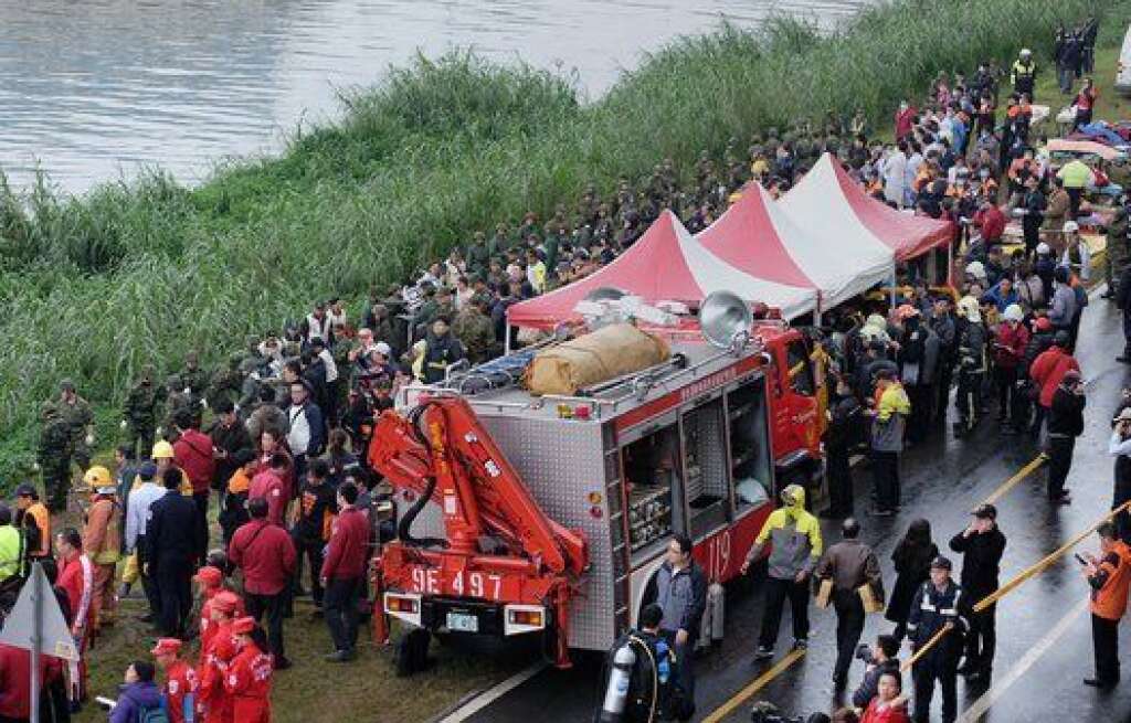 Rescue personnel, military and members of the media line up along the shore as rescue operations continue to free passengers from a TransAsia ATR 72-600 turboprop plane (not pictured) that crash-landed into a river (at L) outside Taiwan's capital Taipei in New Taipei City on February 4, 2015. The low-flying passenger plane, TransAsia Flight GE235 with 58 people on board, clipped a road bridge and plunged into the river outside Taiwan's capital with at least three feared dead and dozens trapped inside.   AFP PHOTO / SAM YEH        (Photo credit should read SAM YEH/AFP/Getty Images)
