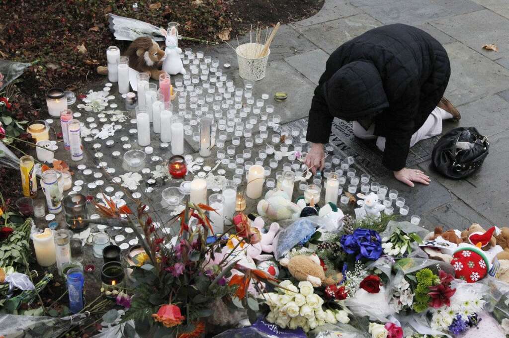 Sandy Hook Elementary School Shooting - A woman pays respects at a memorial outside of St. Rose of Lima Roman Catholic Church, Sunday, Dec. 16, 2012, in Newtown, Conn. On Friday, a gunman allegedly killed his mother at their home and then opened fire inside the Sandy Hook Elementary School in Newtown, killing 26 people, including 20 children. (AP Photo/Julio Cortez)
