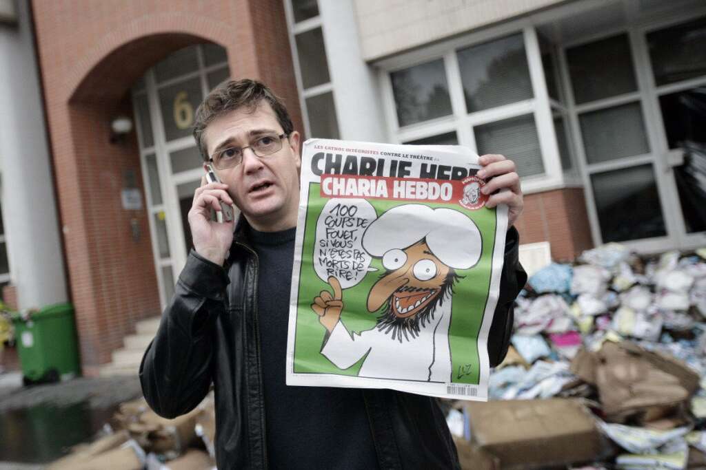 2011 - Charb, l'exemplaire de "Charia Hebdo" à la main devant les locaux incendiés.