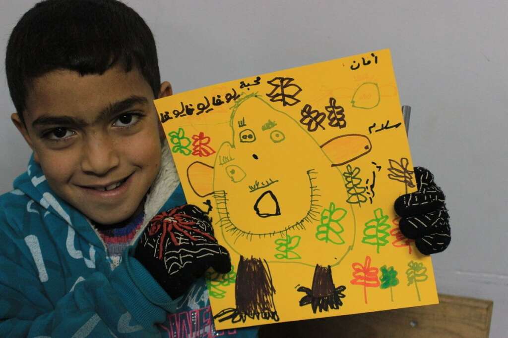 Muhannad, 9 ans - Dans un camp de réfugiés au Liban, Muhannad montre le dessin d'un monstre métaphorique (la guerre) qui mange les bonnes choses, comme les papillons. Au-dessus, on peut lire: "Sécurité, paix et stabilité".