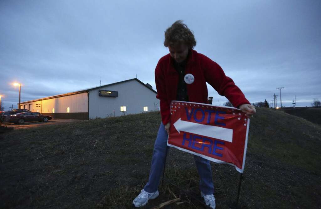 Victoria Collwell - Election Judge Victoria Collwell places a "vote here" sign in the ground in front of the Argusville Firehall Community Center in rural Cass County just before the polls open on Election Day in Argusville, N.D, Tuesday, Nov. 6, 2012. (AP Photo/LM Otero)