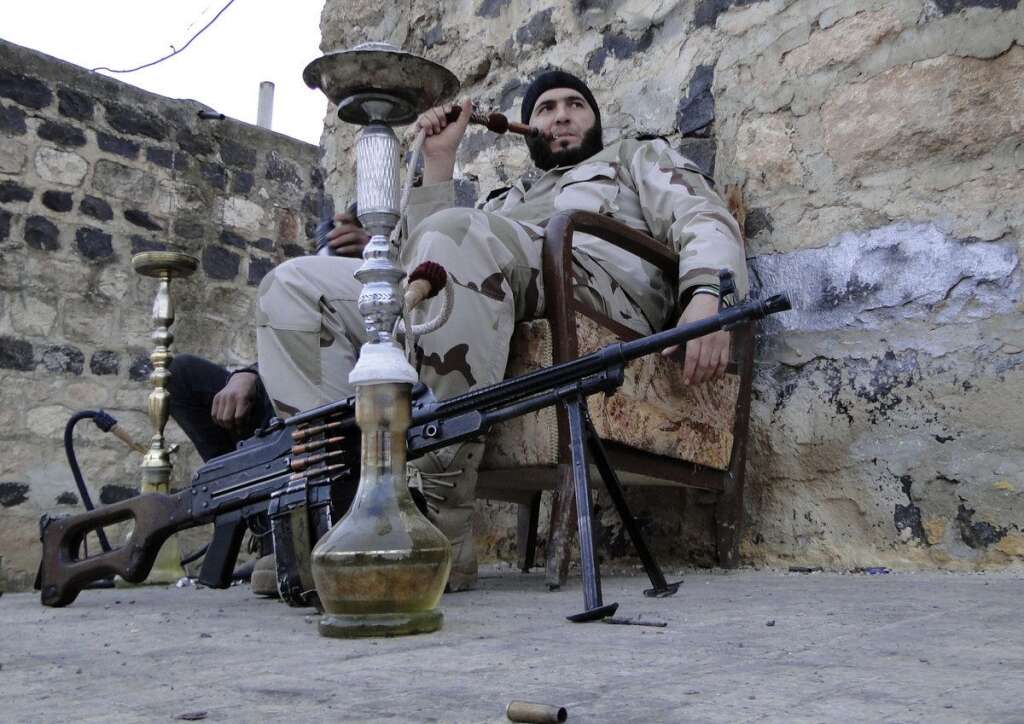 - Un combattant de l'Armée syrienne libre fume le narguilé près de l'aéroport militaire de Menagh, situé près d'Alep, le 25 janvier 2013.