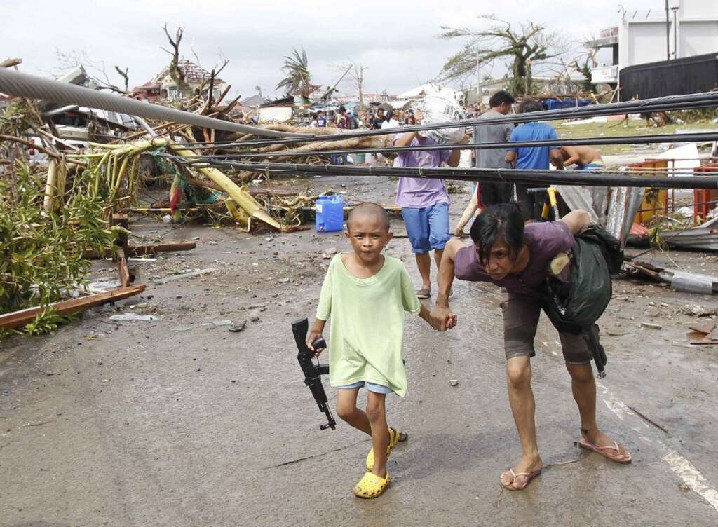 Une mère et son fils marche sous des câbles électriques endommagés à Tacloban - Le 09 Novembre 2013.