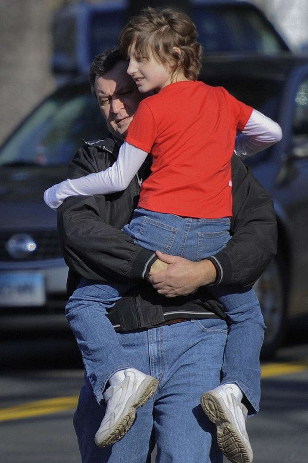 Sandy Hook Elementary School Shooting - A man carries a child away from the area of a shooting at the Sandy Hook Elementary School in Newtown, Conn., about 60 miles (96 kilometers) northeast of New York City, Friday, Dec. 14, 2012. A man opened fire Friday inside two classrooms at the school, killing 26 people, including 20 children. The killer, armed with two handguns, committed suicide at the school and another person was found dead at a second scene, bringing the toll to 28, authorities said. A law enforcement official identified the gunman as 20-year-old Adam Lanza. (AP Photo/Jessica Hill)