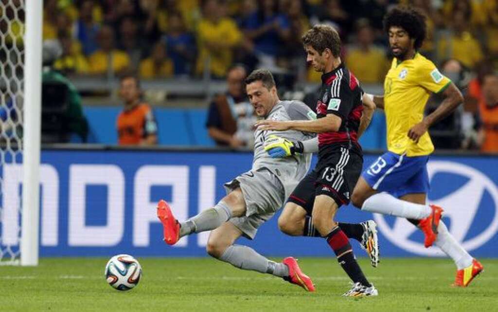 Brazil Soccer WCup Brazil Germany - Brazil's goalkeeper Julio Cesar, left, and Germany's Thomas Mueller challenge for the ball during the World Cup semifinal soccer match between Brazil and Germany at the Mineirao Stadium in Belo Horizonte, Brazil, Tuesday, July 8, 2014. (AP Photo/Frank Augstein)