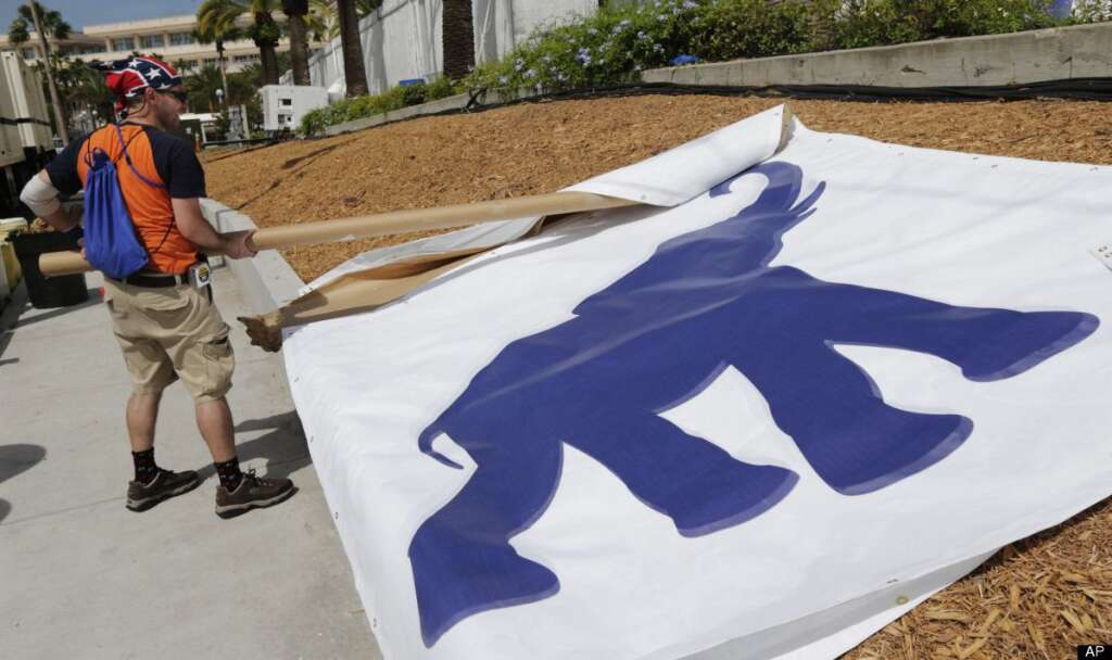 Anthony Batri, from Largo, Fla., unfurls banners as preparations are made ahead of the Republican National Convention in Tampa, Fla., on Saturday, Aug. 25, 2012. (AP Photo/Dave Martin)