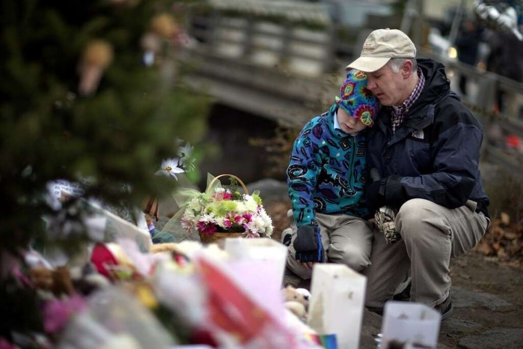 Sandy Hook Elementary School Shooting - David Freedman, right, kneels with his son Zachary, 9, both of Newtown, Conn., as they visit a sidewalk memorial for the Sandy Hook Elementary School shooting victims, Sunday, Dec. 16, 2012, in Newtown, Conn. A gunman walked into Sandy Hook Elementary School in Newtown Friday and opened fire, killing 26 people, including 20 children. (AP Photo/David Goldman)