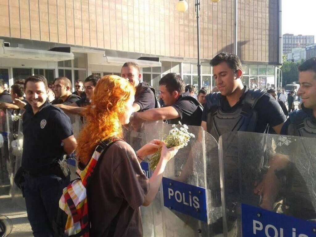 Manifestante offrant des fleurs à un policier - La femme en rouge est devenue un leitmotiv pour la jeunesse féminine qui manifeste pacifiquement en Turquie.
