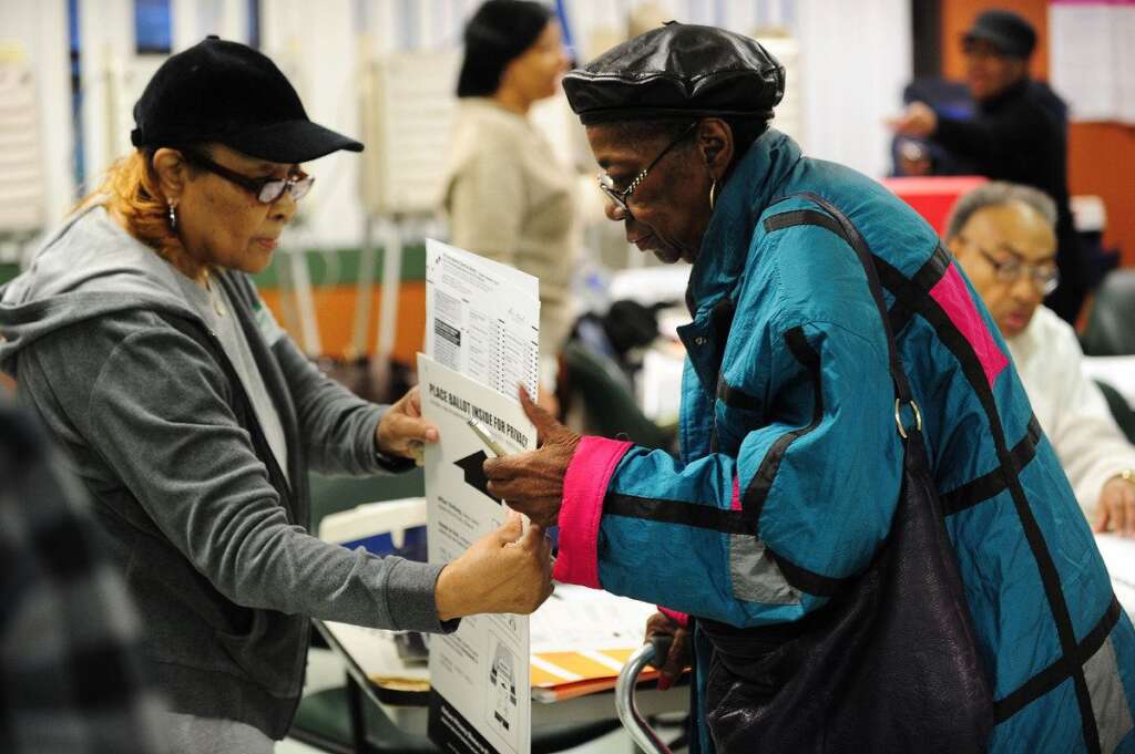 US-VOTE-2012-ELECTION - A poll worker (L) helps a voter (R) with her ballot  in the US presidential election November 6, 2012 at a polling station in Chicago, Illinois.  The final national polls showed an effective tie, with either US President Barack Obama or Republican challenger Mitt Romney favored by a single point in most surveys, reflecting the polarized politics of a deeply divided nation.  AFP PHOTO / Robyn Beck        (Photo credit should read ROBYN BECK/AFP/Getty Images)