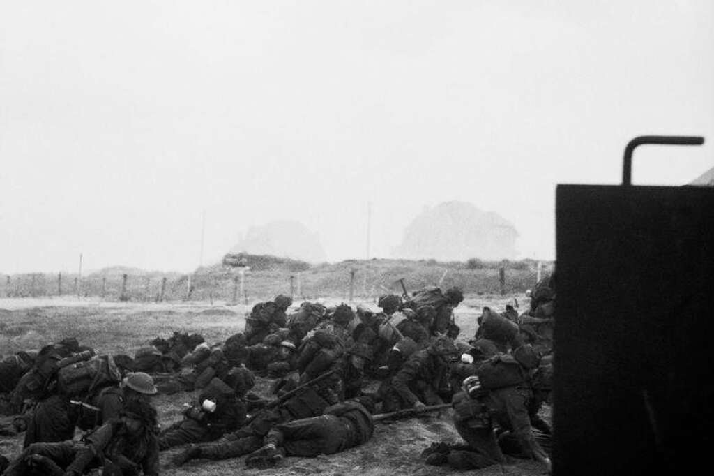 A l'abri avant l'assaut - Ces soldats britanniques reconnaissables à leur casque aplati s'abritent avant de prendre d'assaut la Queen Beach, un des secteurs de Sword Beach. 30.000 hommes y débarquèrent le 6 juin.