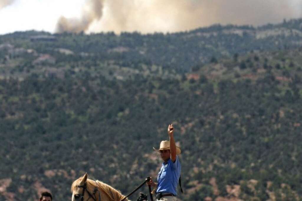 Stephanie Stover, with the City of Colorado Springs, directs traffic away after a mandatory evacuation was announced for the Garden of The Gods due to a wildfire burning west of Colorado Springs, Colo. on Saturday, June 23, 2012. The fire has grown to an estimated 600 acres and The Gazette reports authorities are evacuating the exclusive Cedar Heights neighborhood as well as the Garden of the Gods. (AP Photo/Bryan Oller)