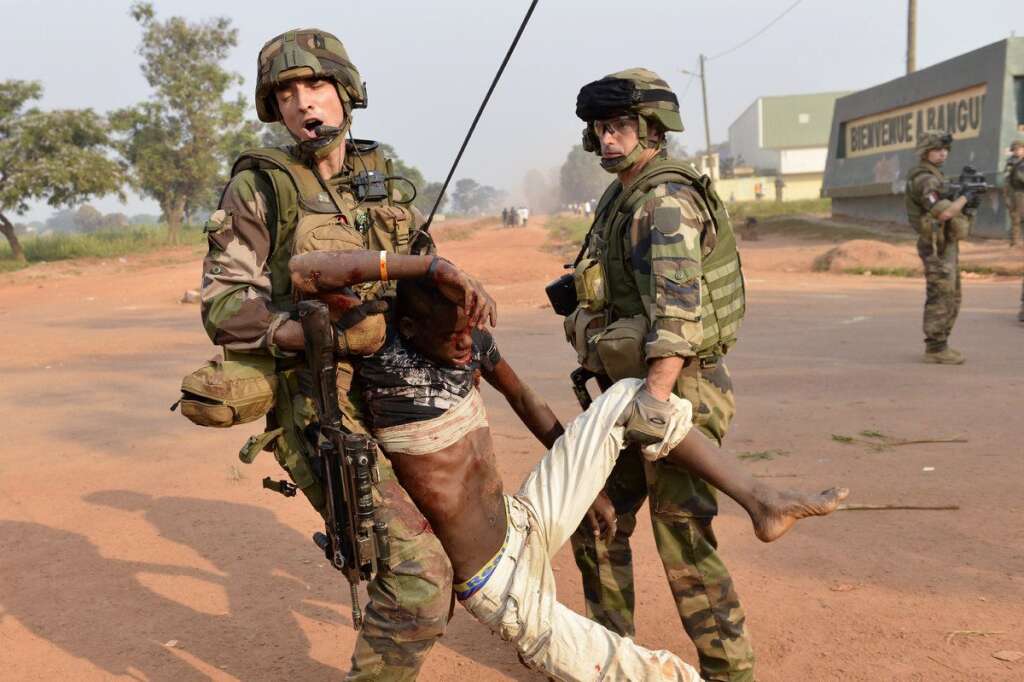 VUE PAR L'AFP - Si l'armée française insiste sur l'aide médicale délivrée par les troupes, elle fait néanmoins l'impasse sur les échanges de tirs parfois nourris qui opposent ses soldats aux rebelles. Ici, deux soldats français évacuent le cadavre d'un manifestant abattu aux alentours de l'aéroport de Bangui, le 23 décembre 2013.
