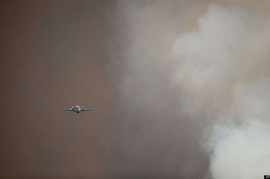 A slurry plane flies through smoke from a wildfire burning west of Manitou Springs, Colo., on Sunday, June 24, 2012. The fire erupted and grew out of control to more than 3 square miles early Sunday, prompting the evacuation of more than 11,000 residents and an unknown number of tourists. (AP Photo/The Colorado Springs Gazette, Christian Murdock)