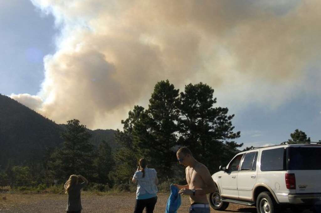 Simon Wach, right, his sister Susan Fox and her daughter Karalea watch a plume of smoke rise from the Waldo Canyon Fire burning near Colorado Springs, Colo., on Monday, June 25, 2012. The fire, one of at least a half-dozen wildfires in Colorado as of Monday, has blackened 5.3 square miles and displaced about 6,000 people since it started Saturday. (AP Photo/Bryan Oller)