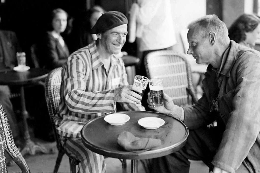 L'arrivée de déportés au Lutetia en 1945 - Deux anciens déportés encore vêtus du vêtement rayé partagent une bière à la terrasse d'un café à leur arrivée au centre de l'hôtel Lutetia à Paris au mois de mois 1945.