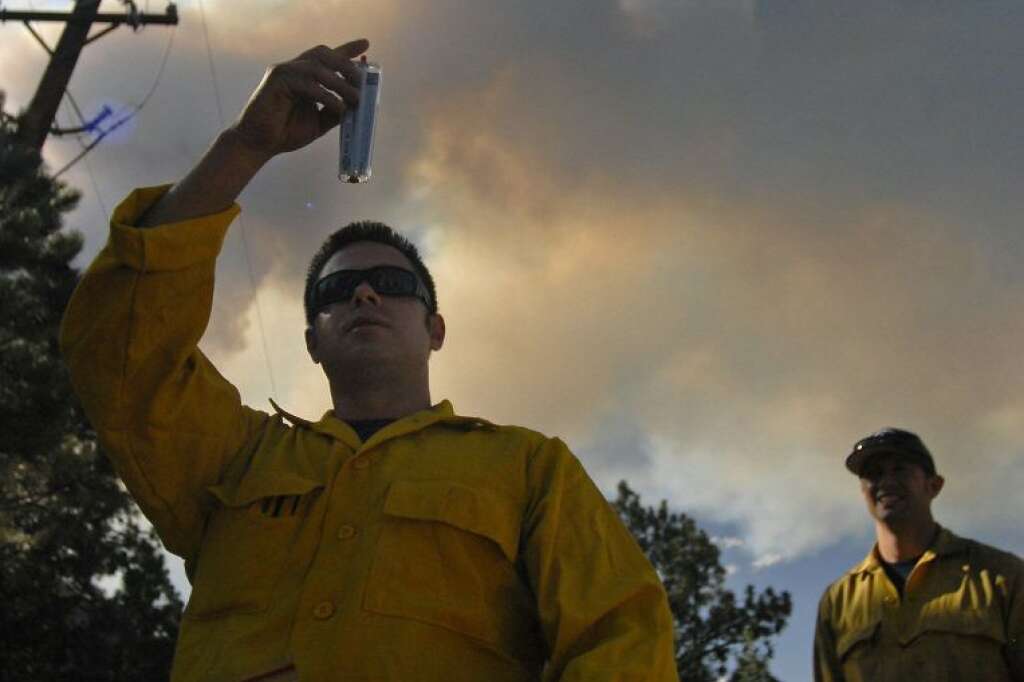 Ken Anderson, a firefighter with the the Colorado Springs Fire Department Task Force I unit, takes a weather reading as large plume of smoke rises from the Waldo Canyon Fire burning near Colorado Springs, Colo., on Monday, June 25, 2012. The fire, one of at least a half-dozen wildfires in Colorado as of Monday, has blackened 5.3 square miles and displaced about 6,000 people since it started Saturday. (AP Photo/Bryan Oller)