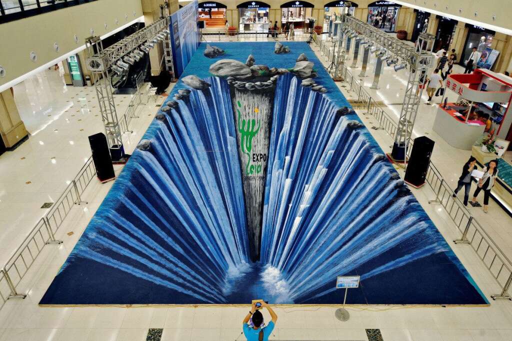 - A man takes a picture of a huge three-dimensional painting made on the floor of a shopping mall by German artist Edgar Muller in Shanghai on August 6, 2009. Muller created the 300-square-meter painting to promote Shanghai's 2010 World Expo.    (Photo credit should read PHILIPPE LOPEZ/AFP/Getty Images)