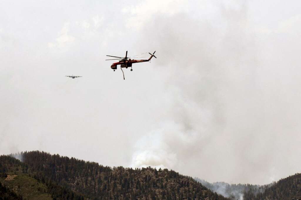 A helicopter and another aircraft battle the Waldo Canyon Fire near Colorado Springs, Colo., on Monday, June 25, 2012. The fire, one of at least a half-dozen wildfires in Colorado as of Monday, has blackened 5.3 square miles and displaced about 6,000 people since it started Saturday. (AP Photo/Bryan Oller)