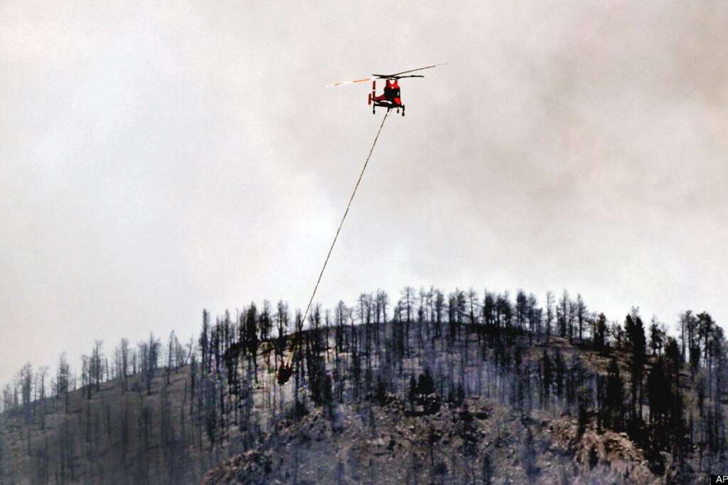 Waldo Canyon Wildfire - A firefighting helicopter flies over burned trees as it goes to refill its bucket while fighting the Waldo Canyon wildfire west of Manitou Springs, Colo., on Monday, June 25, 2012. (AP Photo/Ed Andrieski)