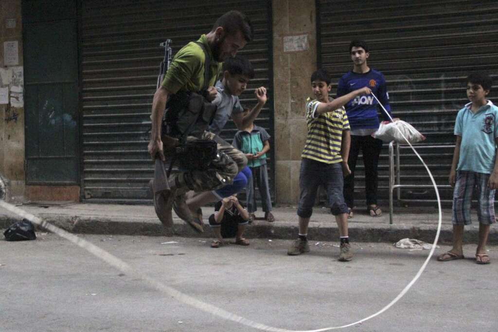 - Un combattant de l'Armée syrienne libre joue à la corde-à-sauter avec des enfants, dans une rue d'Alep. Le 23 août 2013.