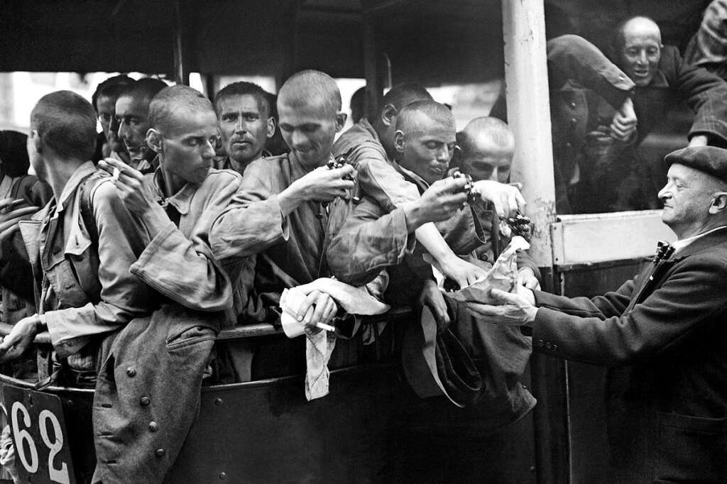 L'arrivée de déportés au Lutetia en 1945 - Photo prise en mai 1945 des déportés français libérés des camps, accueillis à leur arrivée au centre de l'hôtel Lutétia. Un homme leur offre des cerises.