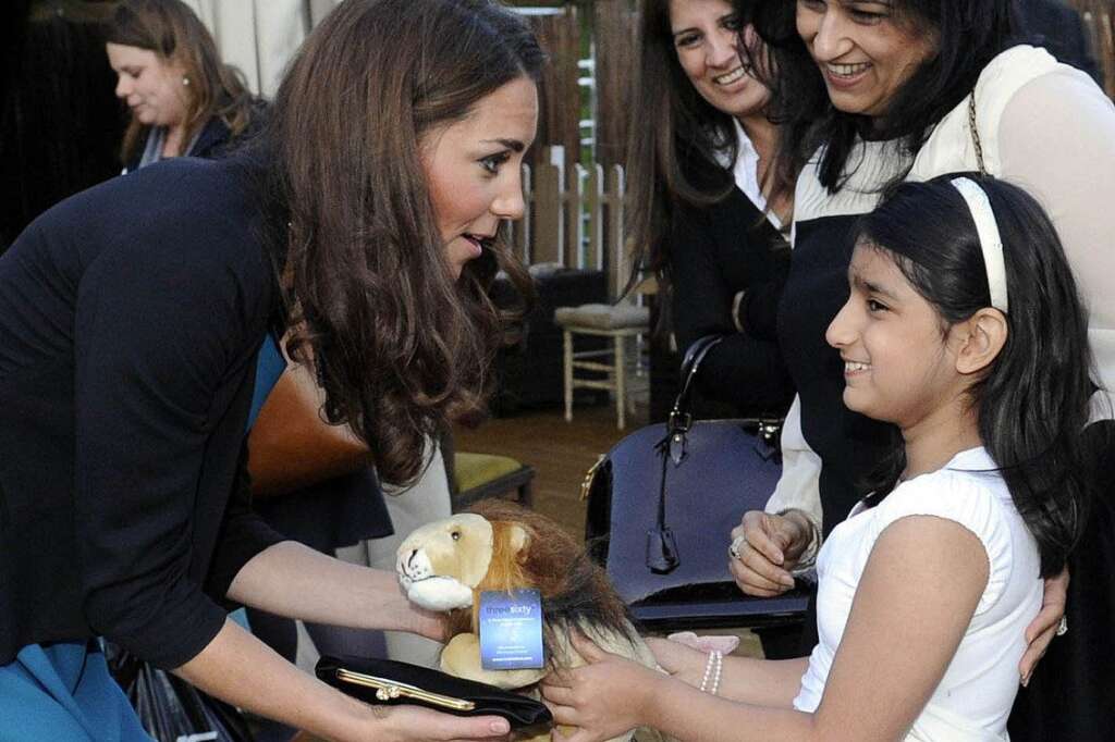 Suhani Kapoor (R) gives an Aslan lion cu - Suhani Kapoor (R) gives an Aslan lion cuddly toy to Catherine, Duchess of Cambridge, as she hosts 150 children and young people from The Art Room at a performance of 'The Lion, The Witch and The Wardrobe' at Kensington Gardens in London on June 15, 2012.  AFP PHOTO / POOL / Rebecca Naden        (Photo credit should read REBECCA NADEN/AFP/GettyImages)