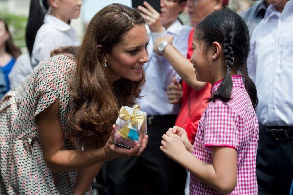 SINGAPORE-BRITAIN-ROYALS - Catherine, the Duchess of Cambridge, receives a gift from a girl during her visit to Strathmore Green, a precinct in Queenstown, a residential district of Singapore on September 12, 2012.  Britain's Prince William and his wife Catherine arrived in Singapore on September 11 to kick off a nine-day Southeast Asian and Pacific tour marking Queen Elizabeth II's Diamond Jubilee.   AFP PHOTO / POOL / Nicolas ASFOURI        (Photo credit should read NICOLAS ASFOURI/AFP/GettyImages)