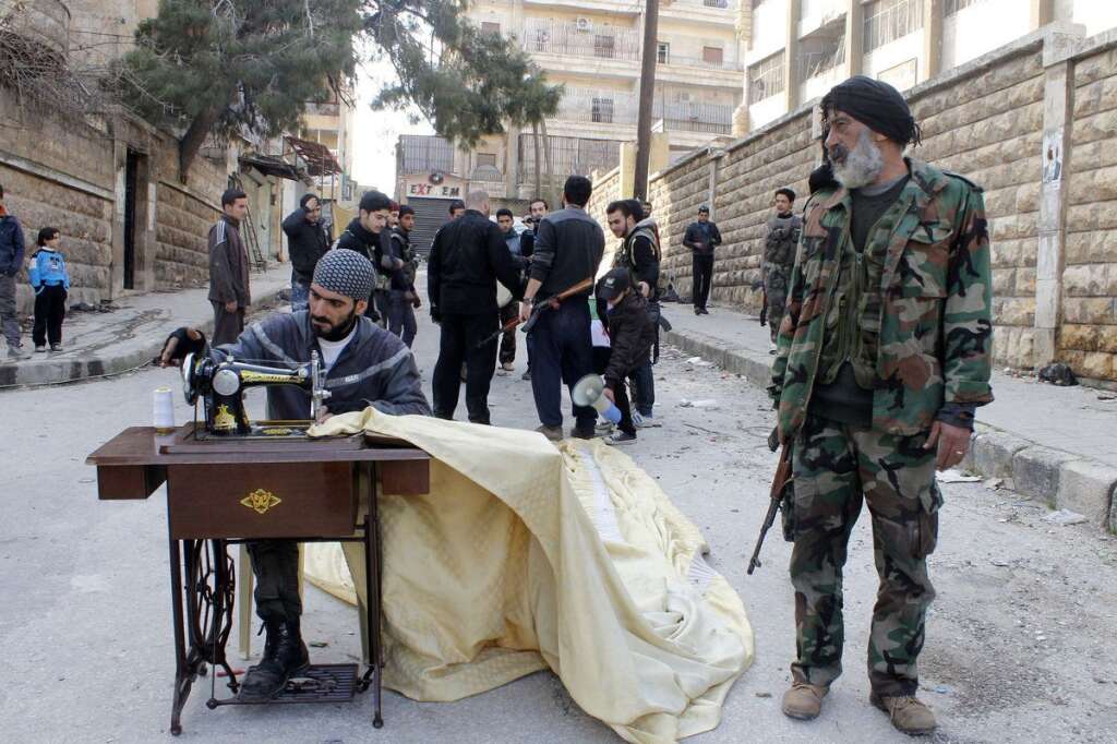 - Un rebelle coud une toile, à Alep, le 24 février 2013.