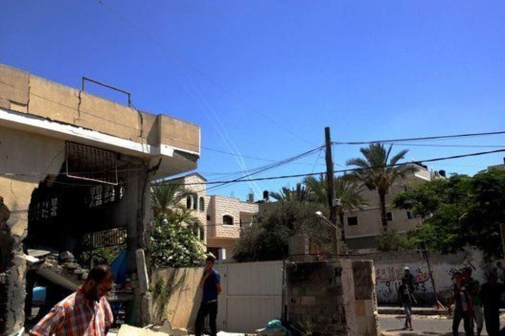 - Des amis et voisins évaluent les dégâts sur la maison de M. Nasser al-Tatar après un raid aérien israélien dimanche. Les tirs de roquettes à partir d'un quartier voisin laissent des traces blanches dans le ciel.