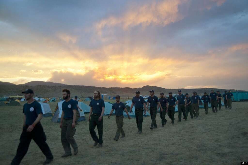 In a photo made on Tuesday, June 19, 2012, and made available on Wednesday by the Colorado National Guard, firefighters from the Monument, Colo., fire department march to dinner at sunset in a base camp near the High Park wildfire about 15 miles west of Fort Collins, Colo.(AP Photo/Colorado National Guard, John Rohrer)