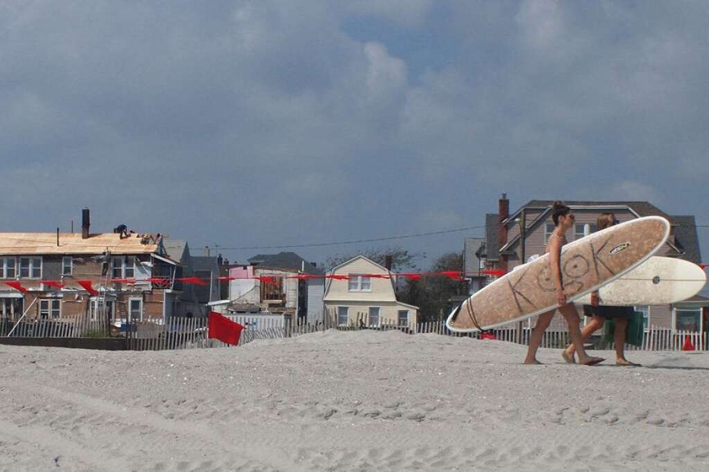 Surfeuses à Rockaway Beach - Un an après le passage de l’ouragan Sandy, des dizaines de maisons sont toujours en reconstruction sur le front de mer de cette plage, située à une heure de métro de Manhattan.