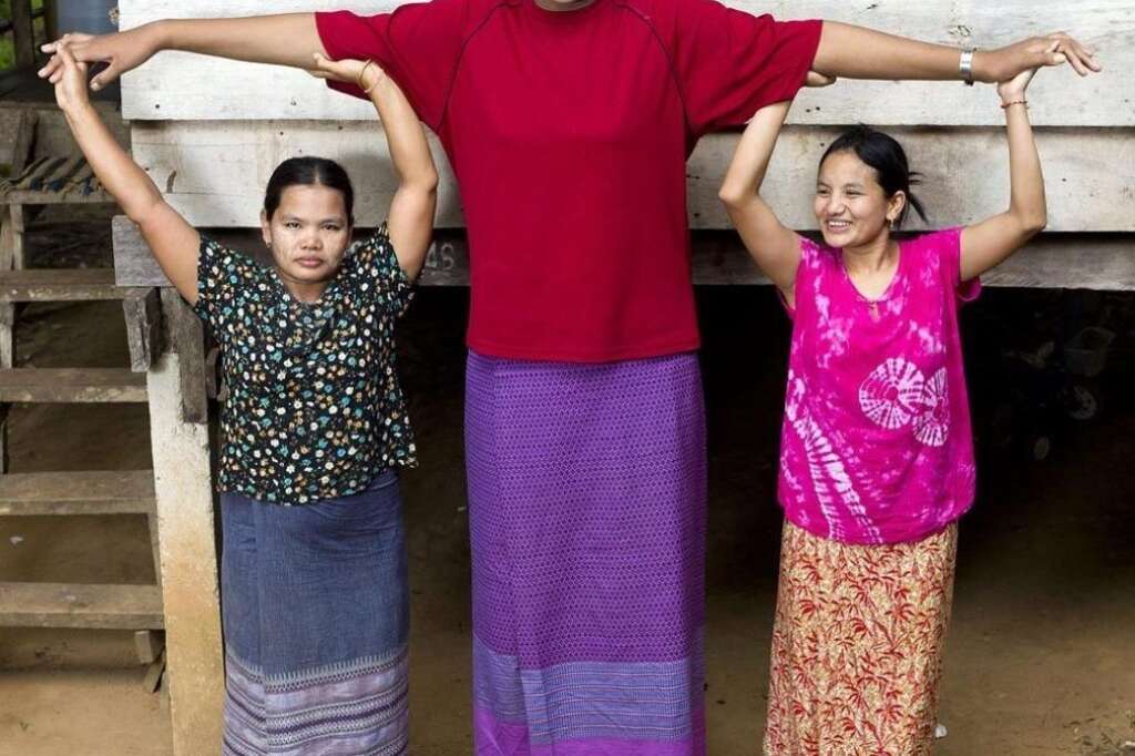 World's Tallest Teen Girl - Malee Duangdee, 18, stands outside her home with her relatives Mai Khosod, 37, and A Khosod, 24, who are holding her arms up on April 7, 2011, in Trat Province, Thailand. Towering head and shoulders above her own parents this giant teenager -- at 6 feet 10 inches -- is the tallest in the world and could still be growing.