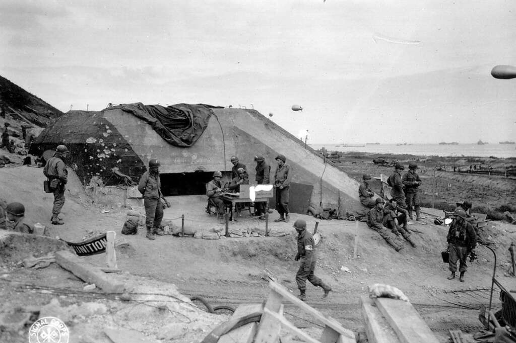 Le danger des bunkers allemands - Ces places fortes qui abritent l'artillerie côtière et des mitrailleuses allemandes coûteront très cher en vies humaines. Ici, des soldats américains autour d'un bunker capturé sur Omaha Beach.