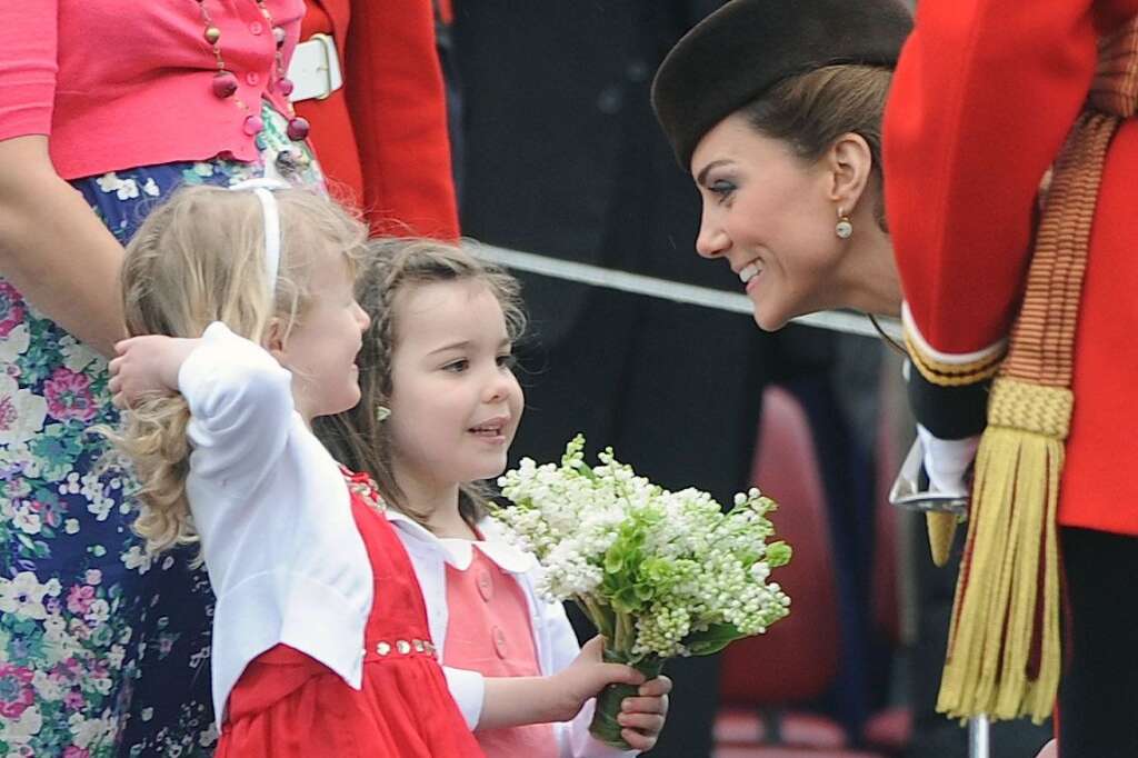 The Duchess Of Cambridge Visits The Irish Guards On Their St Patrick's Day Parade - ALDERSHOT, ENGLAND - MARCH 17:  Catherine, Duchess of Cambridge meets two young girls, who handed her a delicate posy as she presents shamrocks to members of the 1st Battalion Irish Guards at the St Patrick's Day Parade at Mons Barracks on Saturday March 17, 2012 in Aldershot, England.  450 soldiers were on parade, accompanied by the regimental mascot Conmeal, an Irish wolfhound who received his own sprig of shamrock from the Duchess. This was her first solo military engagement and she will now inherit a tradition which begun in 1901 by Queen Alexandra and more recently carried out for 32 years by the Queen Mother. Prince William is honorary Colonel of the Irish Guards. (Photo by Paul Vicente - WPA Pool/Getty Images)