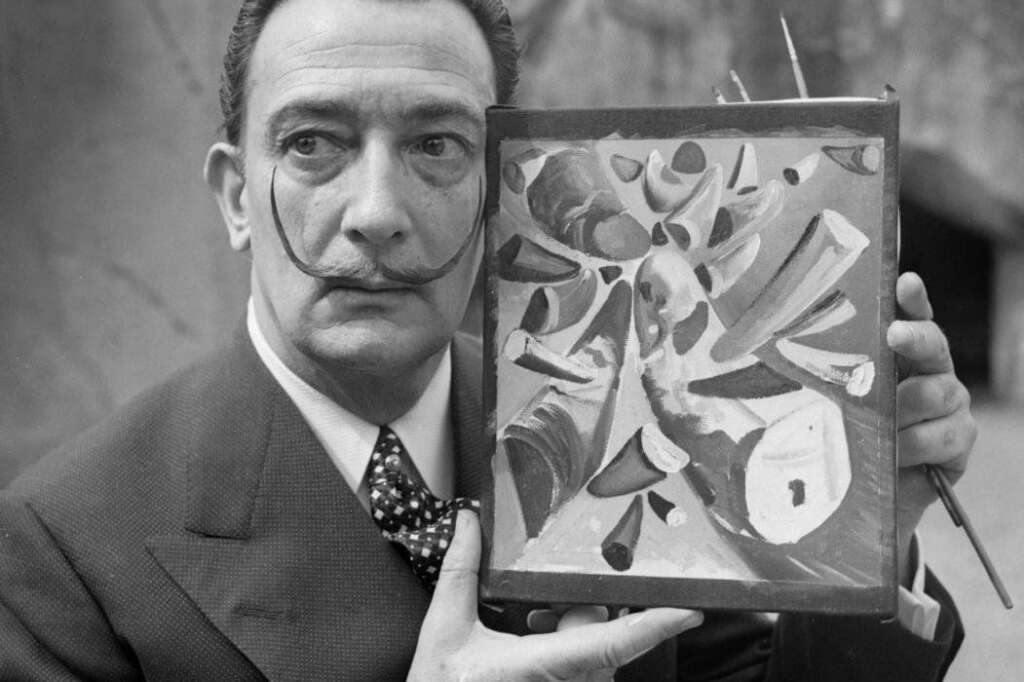 Salvador Dalí - Portrait daté du 30 avril 1955 du peintre espagnol Salvador Dali, l'un des peintres les plus populaires du 20ème siècle, montrant un tableau qu'il vient d'achever au zoo de Vincennes et représentant une collision de cornes de rhinocéros. Né en 1904 à Figueras en Catalogne