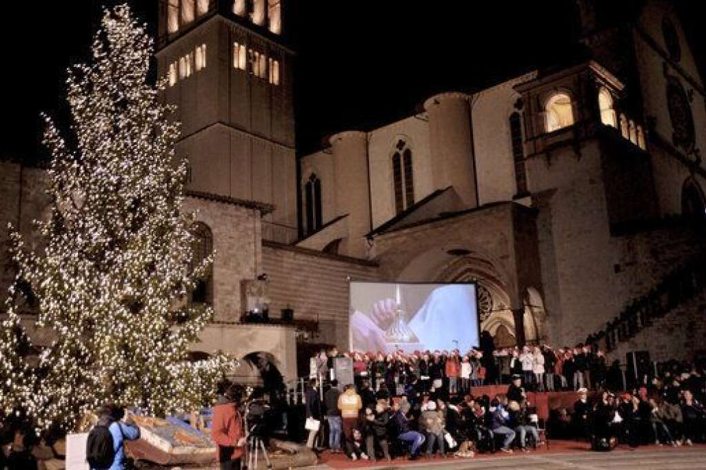 Assise, Italie - En direct du Vatican, le Pape François allume symboliquement un arbre de Noël à 20 kilomètres de là, devant la Basilique Saint-Francis. Le Pape a également allumé une bougie, symbole d'espoir pour les migrants
