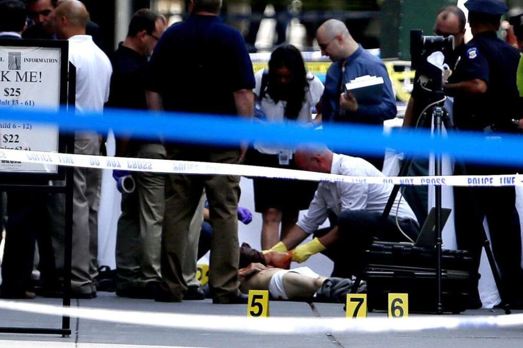 - Officials examine a body near the Empire State Building following a shooting, Friday, Aug. 24, 2012, in New York. New York City Mayor Michael Bloomberg said some of the victims may have been hit by police bullets as police and the gunman exchanged fire. Police say a recently laid-off worker shot a former colleague to death near the iconic skyscraper and then randomly opened fired on people nearby before firing on police. (AP Photo/Julio Cortez)