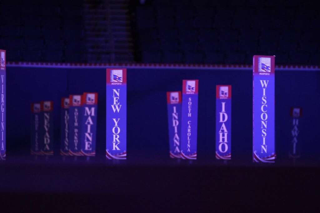 In the dimmed lights, state delagate signs are seen on the convention floor after an abbreviated session of the Republican National Convention in Tampa, Fla., on Monday, Aug. 27, 2012.(AP Photo/David Goldman)