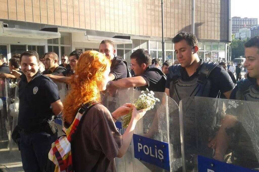Manifestante offrant des fleurs à un policier - La femme en rouge est devenue un leitmotiv pour la jeunesse féminine qui manifeste pacifiquement en Turquie.