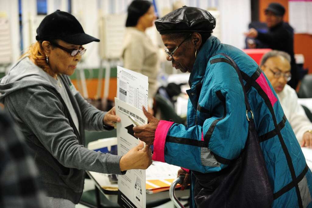 US-VOTE-2012-ELECTION - A poll worker (L) helps a voter (R) with her ballot  in the US presidential election November 6, 2012 at a polling station in Chicago, Illinois.  The final national polls showed an effective tie, with either US President Barack Obama or Republican challenger Mitt Romney favored by a single point in most surveys, reflecting the polarized politics of a deeply divided nation.  AFP PHOTO / Robyn Beck        (Photo credit should read ROBYN BECK/AFP/Getty Images)
