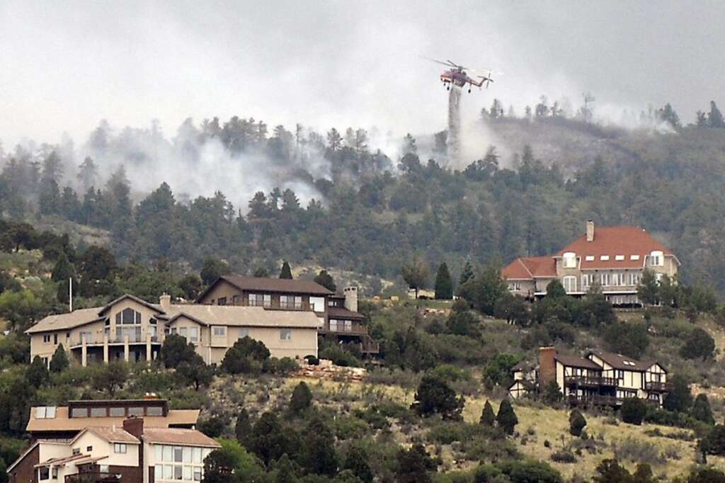 A helicopter battles a wildfire near Colorado Springs, Colo., on Sunday, June 24, 2012. The fire erupted and grew out of control to more than 3 square miles early Sunday, prompting the evacuation of more than 11,000 residents and an unknown number of tourists. (AP Photo/Bryan Oller)
